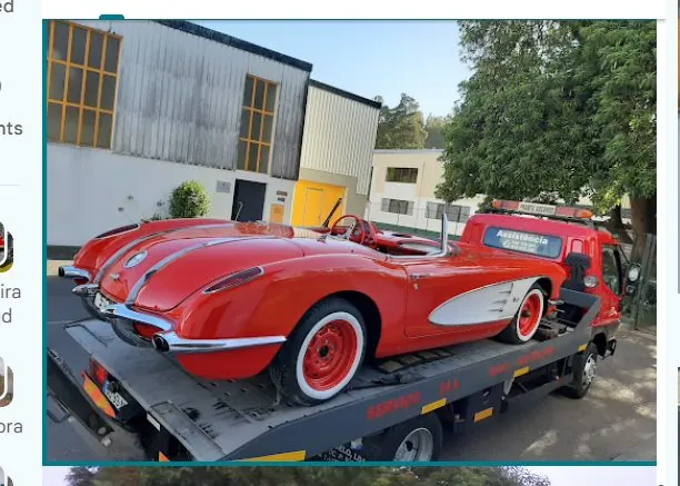 Carro clássico vermelho transportado numa plataforma